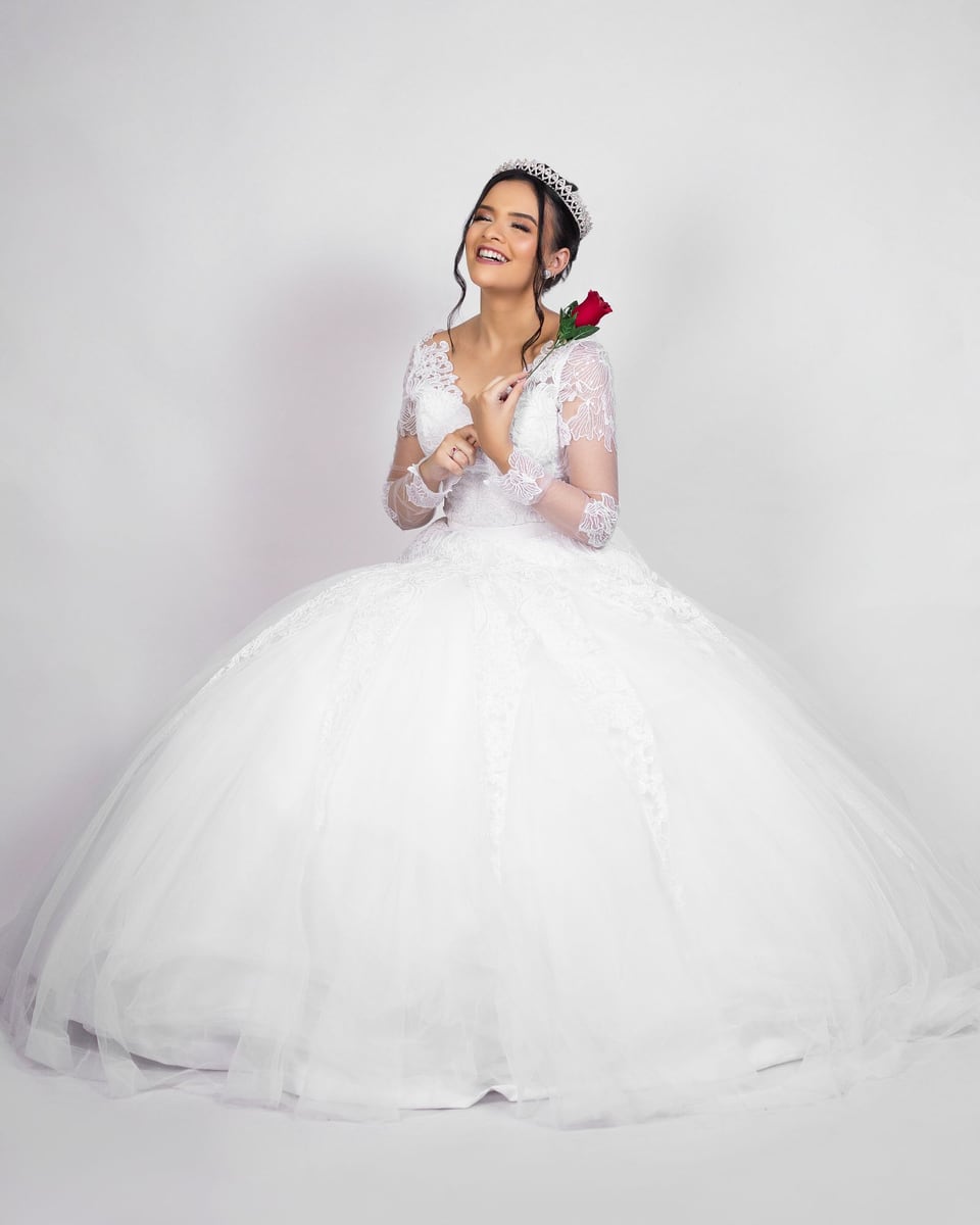 Illustrative photograph of a bride in a full-skirted white gown holding a red rose.